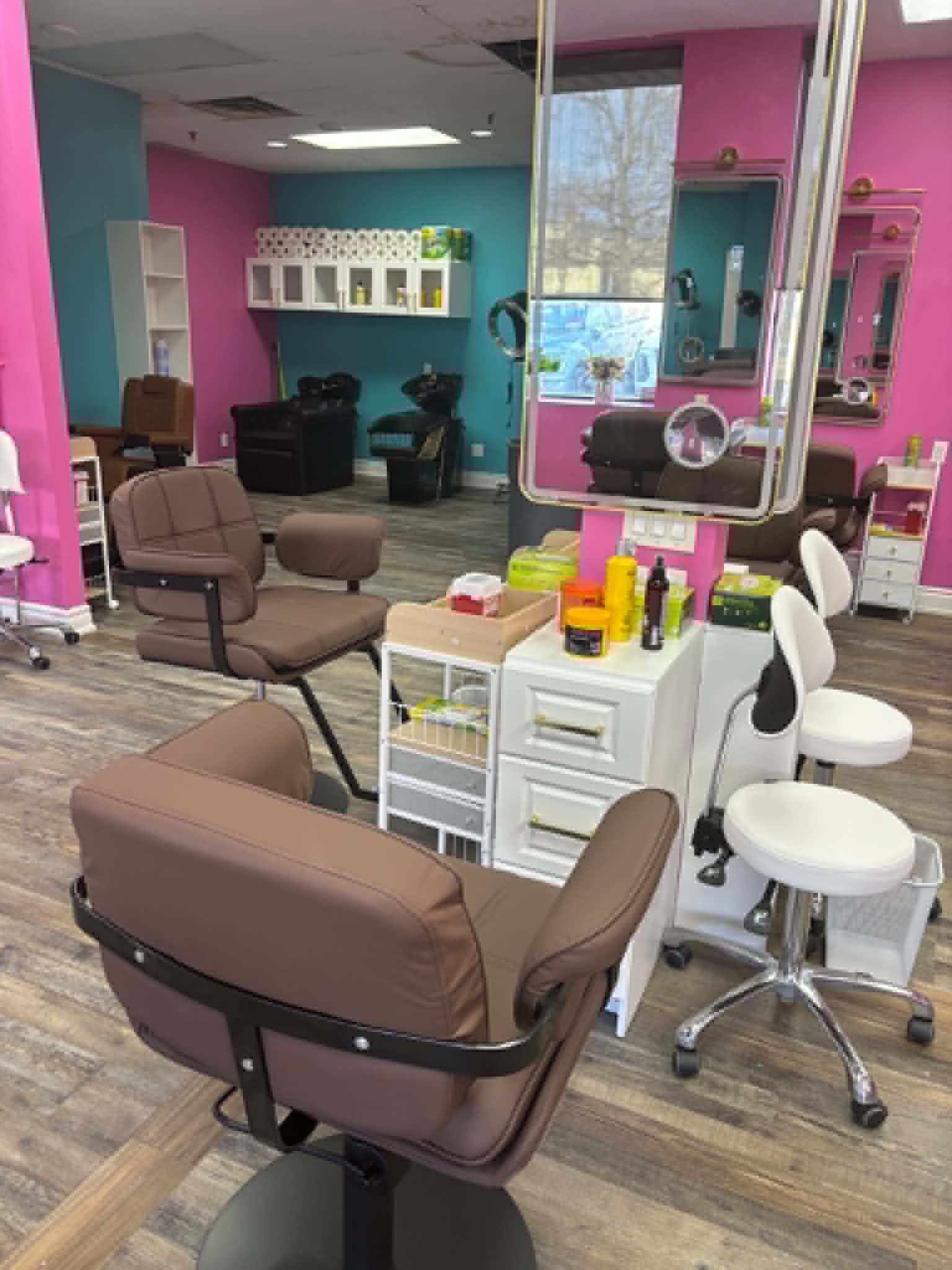 Bilama Salon floor with pink and teal walls, styling stations, and wash area